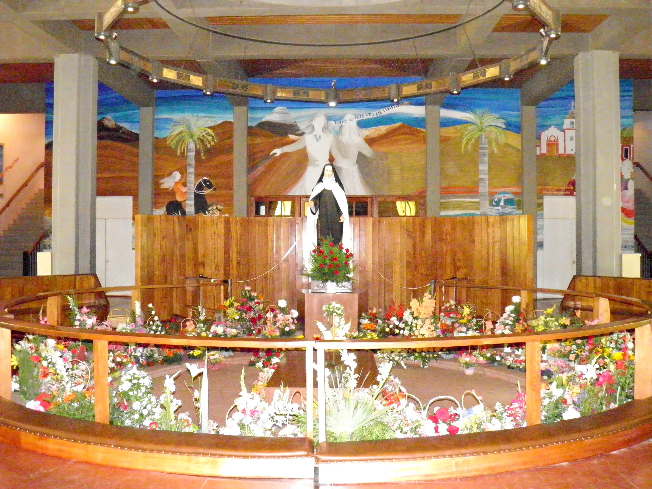 La cripta del santuario: murales coloridos y flores alrededor de la tumba de la santa