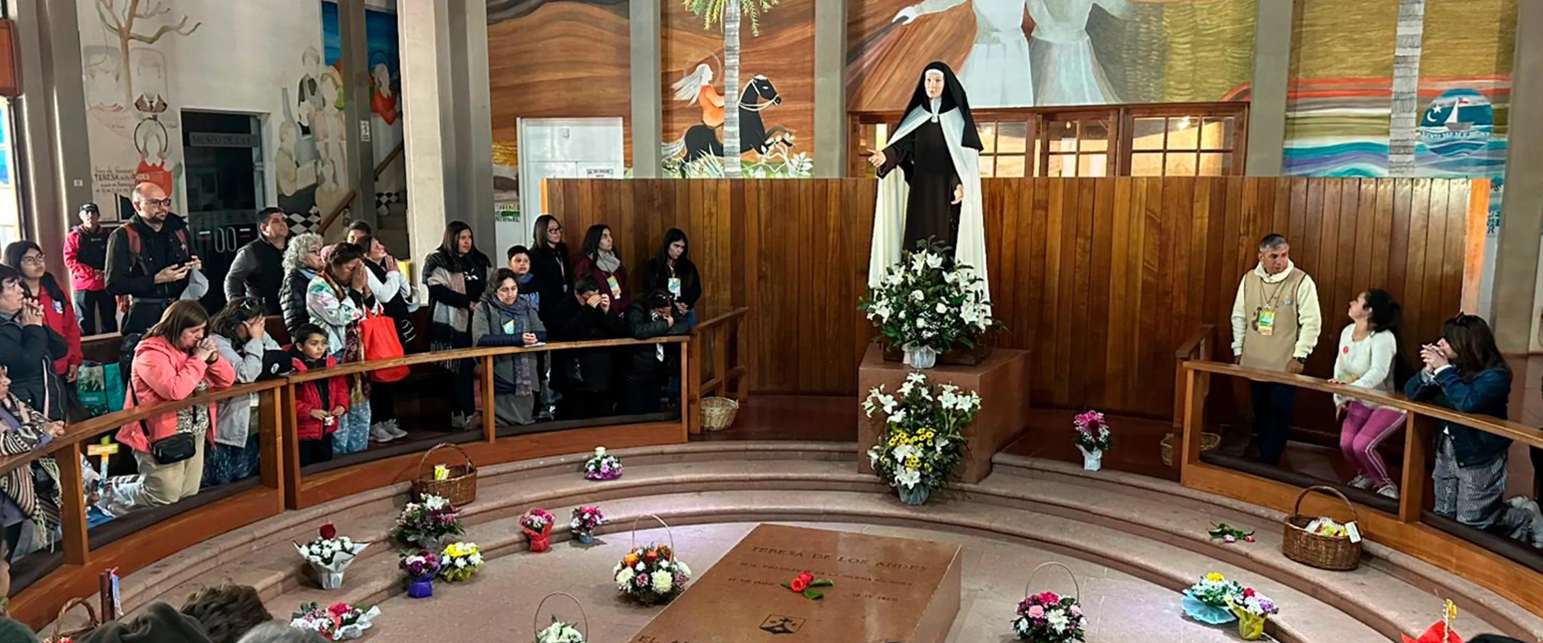 Peregrinos rodean la tumba de Santa Teresa en la cripta durante una celebración