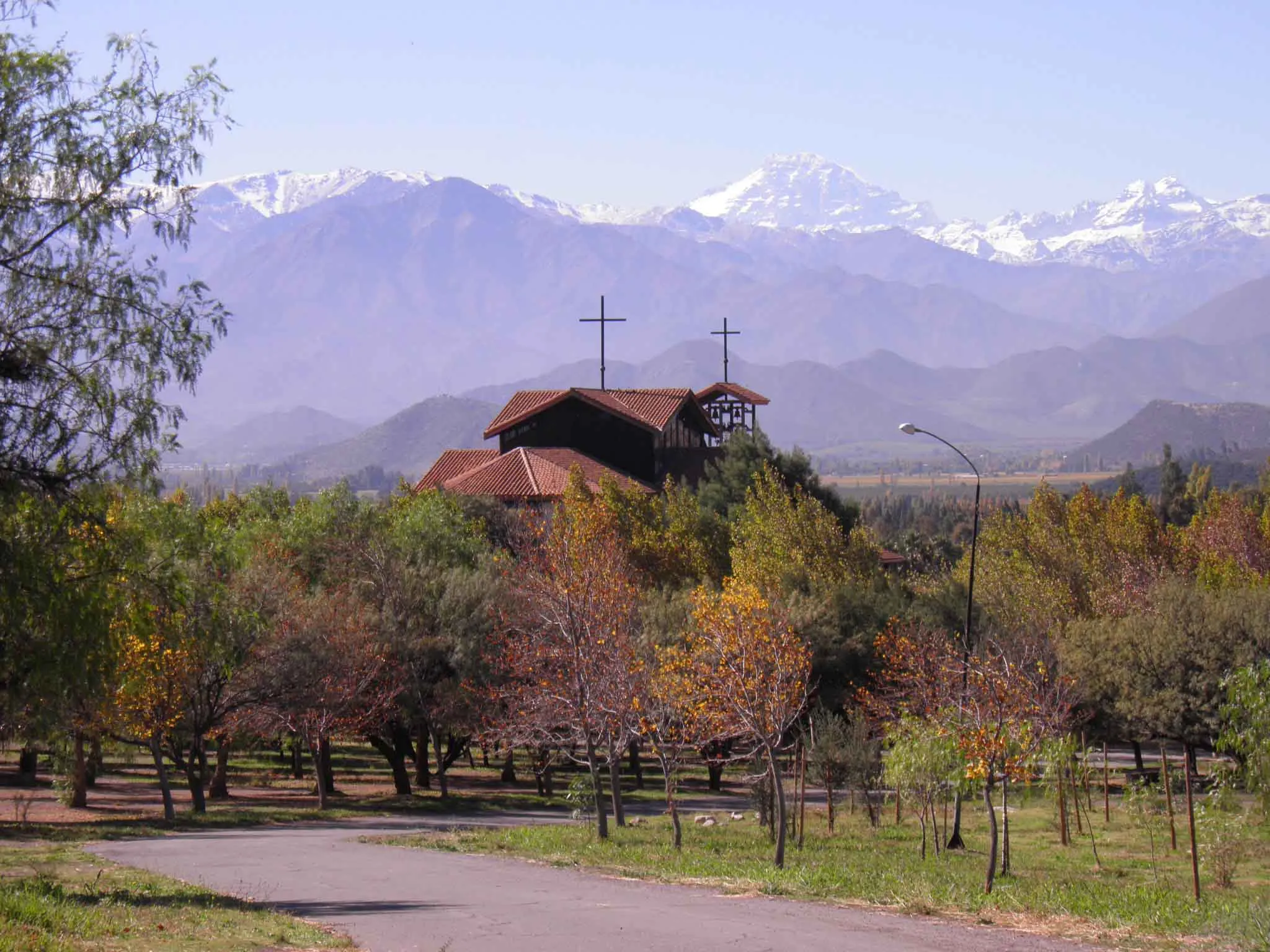 El templo del santuario, de muros blancos y techos de teja, frente a la cordillera nevada de Los Andes